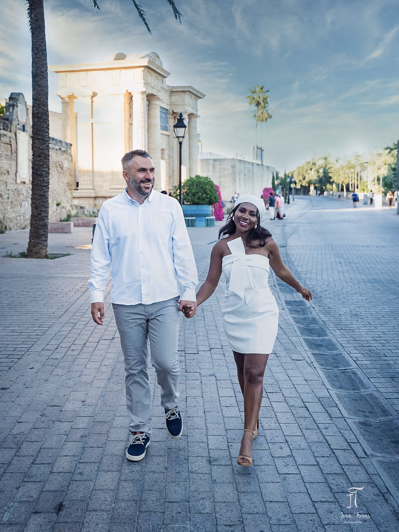 Pablo and Seraphine walking hand in hand along a Córdoba street at golden hour.